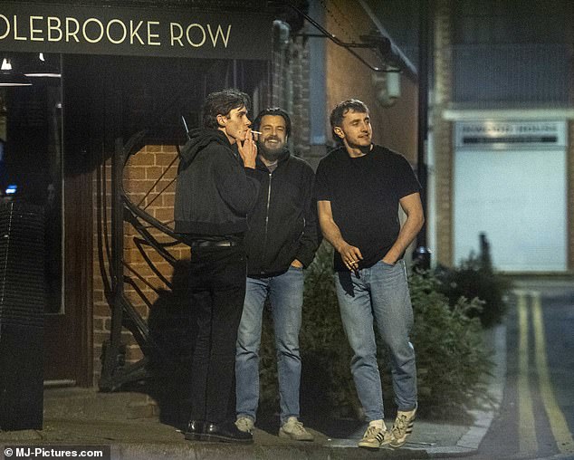 Laid back: Paul sported a black T-shirt and a pair of blue jeans as he smoked a cigarette outside the bar