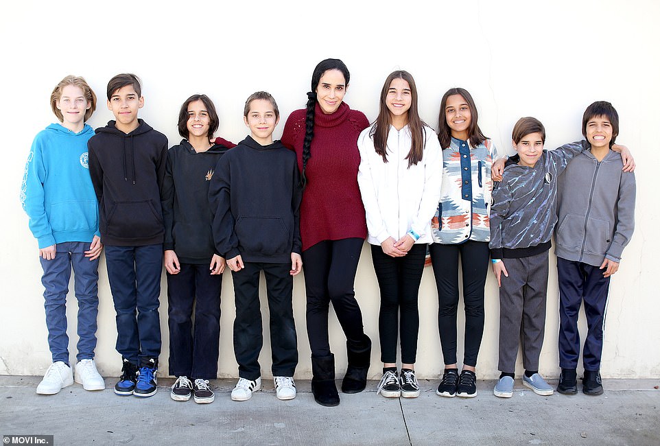 Mommy in the middle: Suleman glowed with pride as she wore a winter-appropriate outfit consisting of a maroon turtleneck top and black pants with her jet-black hair in a braided ponytail