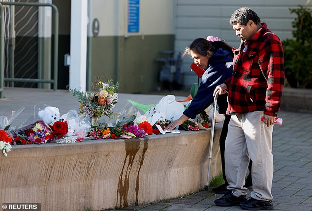 Community members visit a memorial to shooting victims at Mac Dutra Park in Half Moon Bay