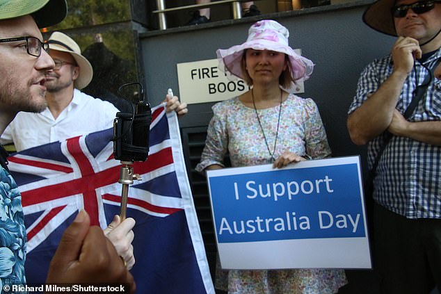 Counter-protesters in support of Australia Day stood outside the Invasion Day rally with the Australian flag and banners (pictured)