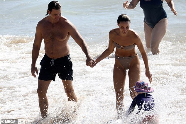 The couple looked very much in love as they held hands on the shore and waded through the water together.