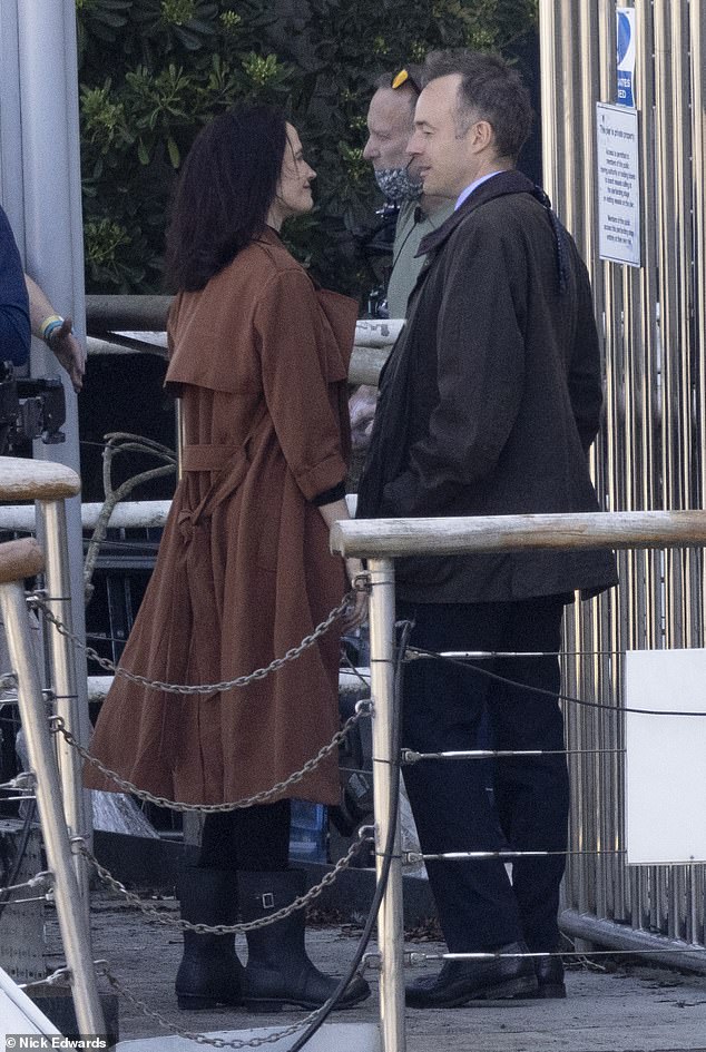 The actress showed off a graceful figure in a bronze coat and black high-necked top while chatting with a male co-star near Tower Bridge.