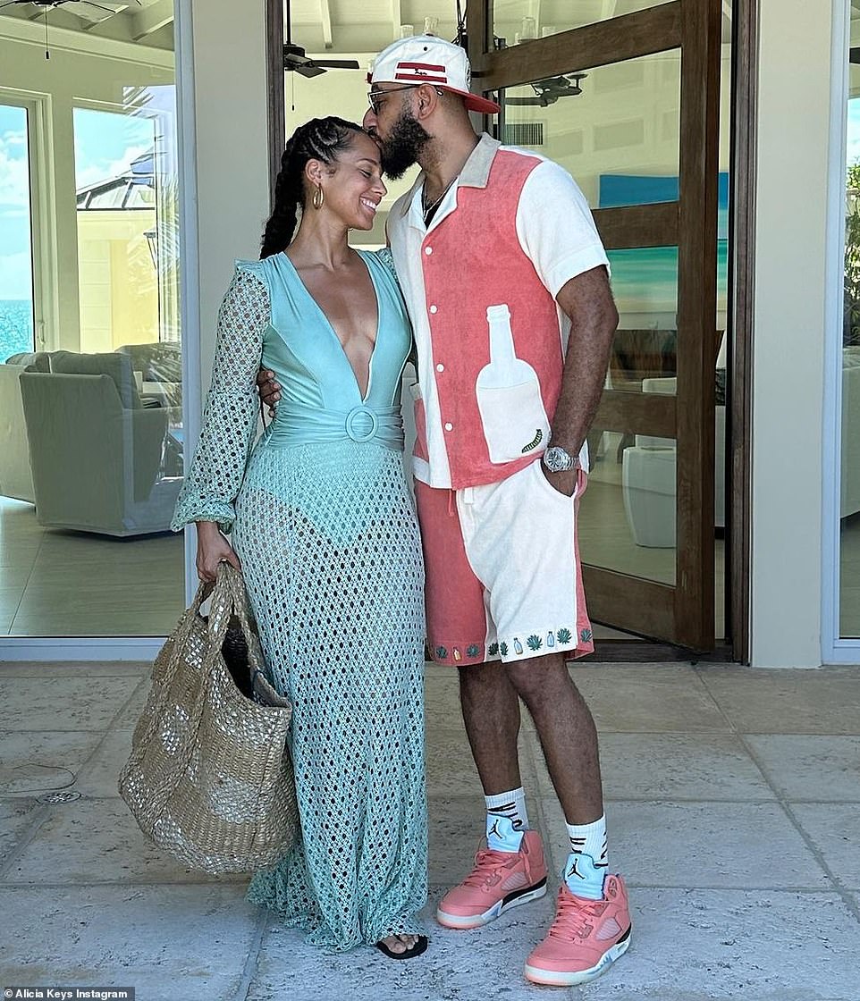 A kiss for your queen: Swizz is seen here giving her a kiss on the forehead while holding a large woven beach bag.