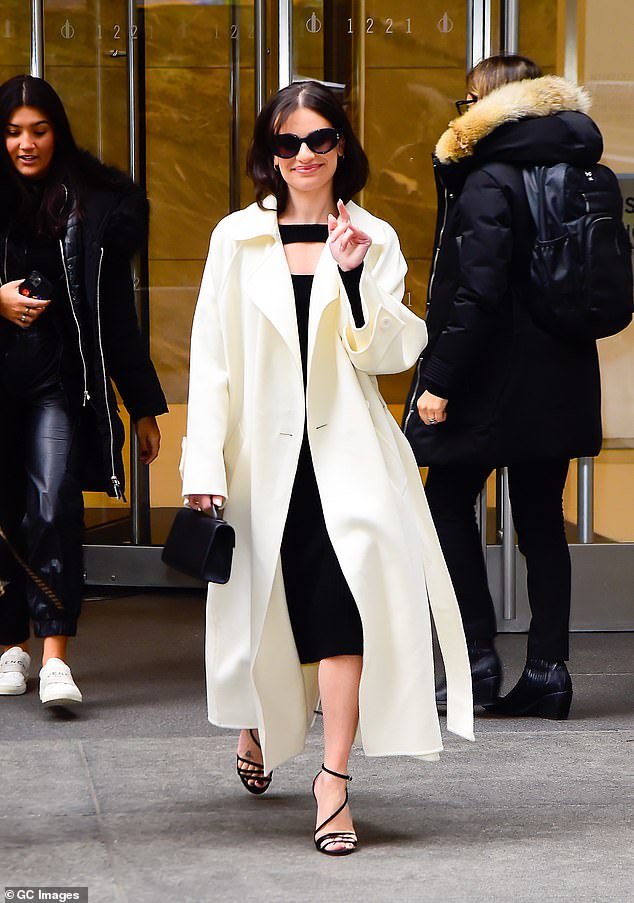 Now in a coat: She also wore medium-sized hoop earrings and kept warm in a classic long white coat.