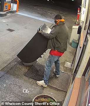 The man in the orange hoodie trying to get the cash back from the machine, even after his partner in crime broke it a bit, but he couldn't either.