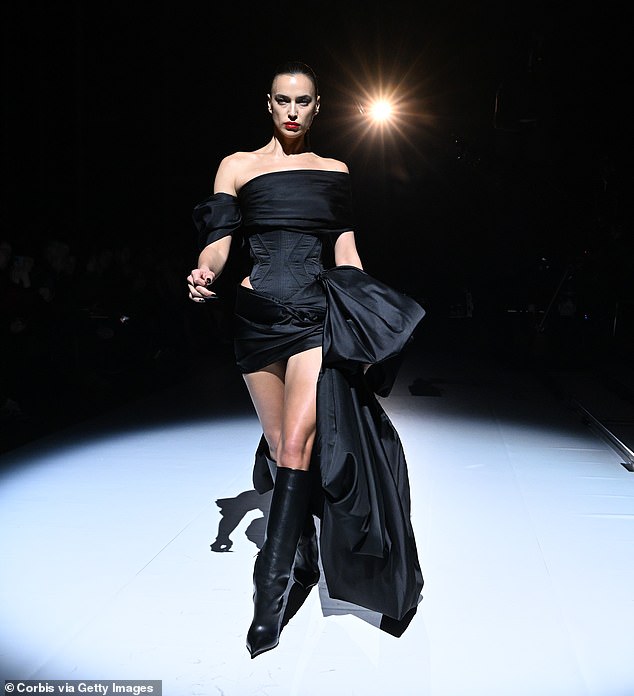 Eye-catching: The model strutted down the runway in knee-high heeled boots, while her dark hair was swept back in a ponytail