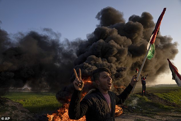 Palestinians burn tires and wave the national flag during a protest against the Israeli military attack in the West Bank city of Jenin, on January 26, 2023.