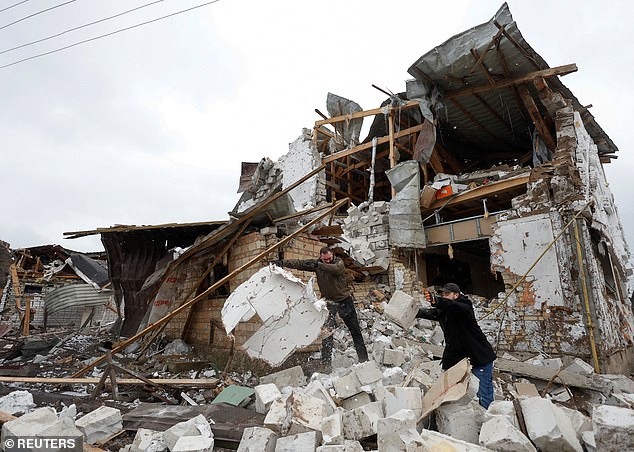 Local residents remove rubble from their neighbor's house damaged by a Russian military attack, amid Russia's attack on Ukraine.