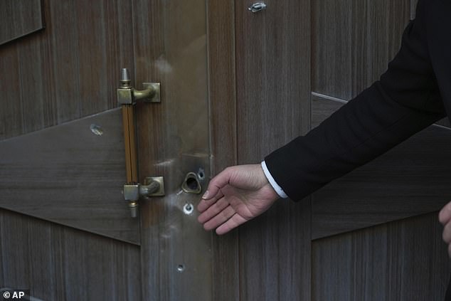 A man gestures at bullet holes left after an attack at the Azerbaijan Embassy in Tehran