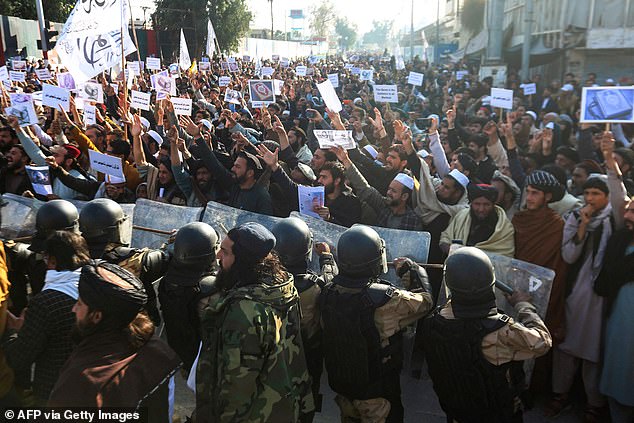 Taliban security forces stand guard as Afghans shout slogans during a protest against the burning of the Koran today