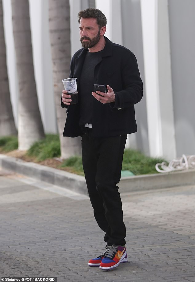 Hollywood hunk: The Accountant star wore his hair short and messy and sported a well-groomed beard while holding a large mug of black coffee