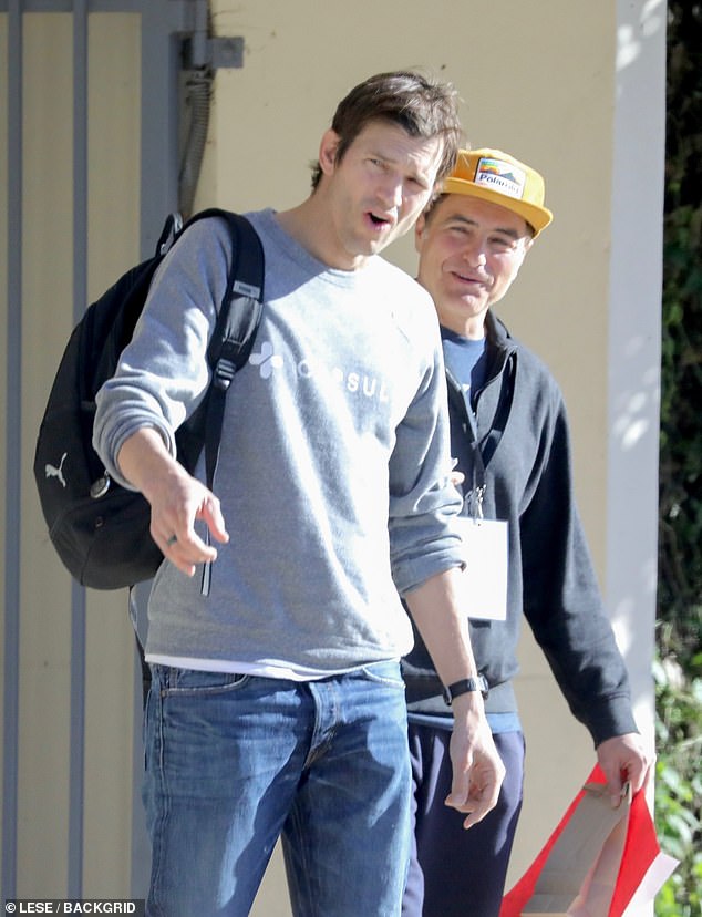 Sweater and Jeans: Kutcher wore a gray sweater and jeans.  He had a large black backpack slung over his right shoulder.