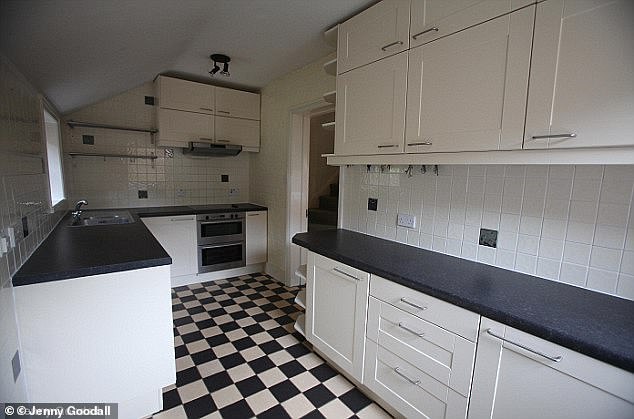 Pictures from 2011 show the kitchen had black and white tile, simple white cabinets, and black work surfaces.