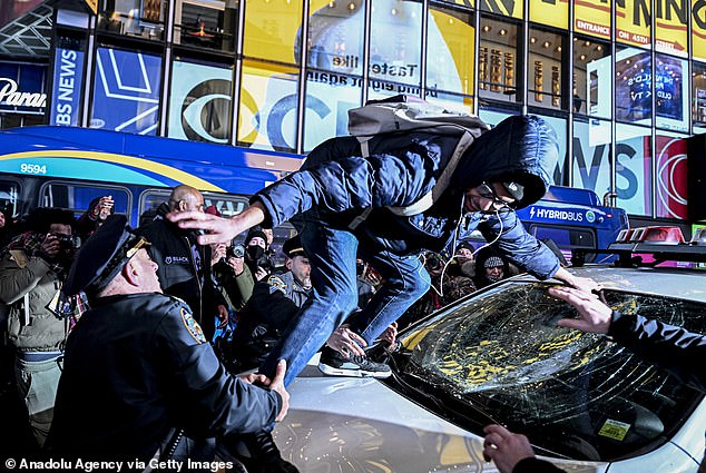 Police officers detain a smiling protester who broke the window of a police car during the protest against the police assault on Tire Nichols in Times Square in New York, the United States, on January 27, 2023.