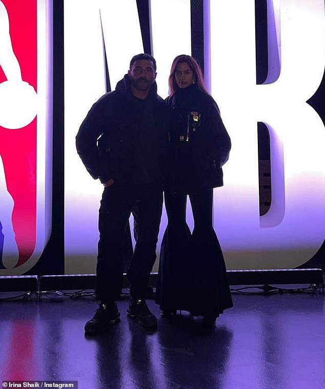 Posing before the game: In an instant, she appears to be arriving at the game through a private entrance with the former Burberry creative director and then they posed together in front of the light-up NBA lettering.