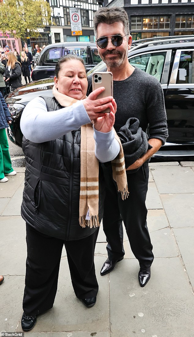 All smiles: He looked strikingly different while wearing a gray long-sleeved T-shirt and black pants as he stopped to take selfies with eager fans.