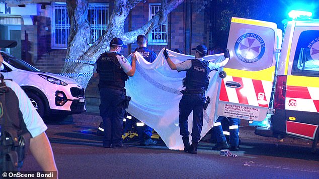 Officers lifted a white blanket (pictured) as they placed the man in an ambulance