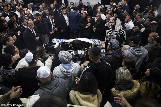 Family and friends of Eli and Natali Mizrahi, who were killed in a shooting in Jerusalem, mourn their funeral.