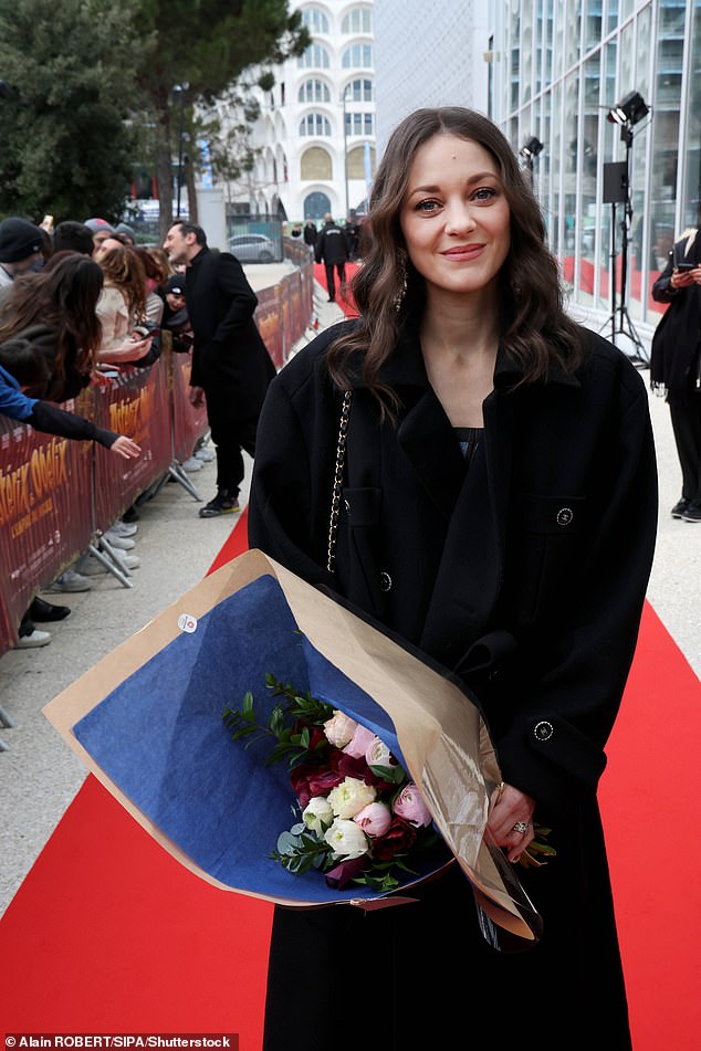 Stunning: The star flashed her gorgeous smile for the cameras while holding a large bouquet of flowers