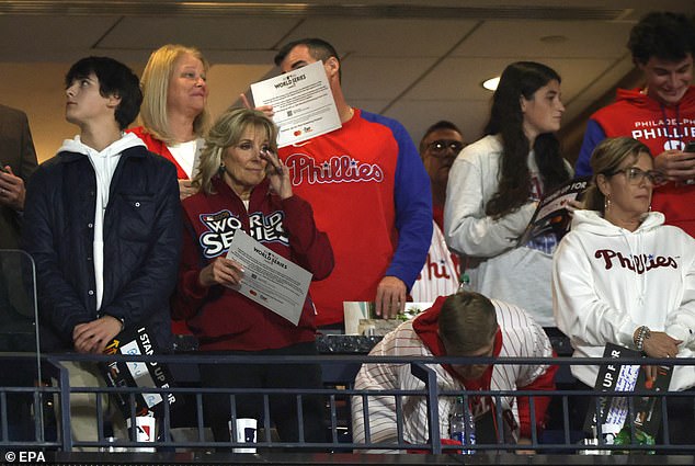 First lady Jill Biden appears to be wiping away a tear after those in attendance for Game 4 of the World Series stood up at a memorial tribute to Stand Up to Cancer on Wednesday night in Philadelphia, a solemn moment during a otherwise raucous event.