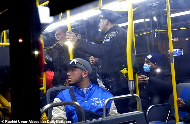 A policeman talks with some of the migrants who have boarded the bus heading to the terminal
