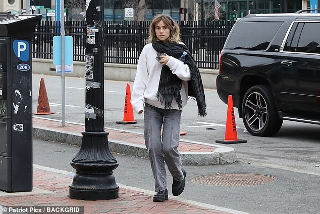 Natural beauty: The catwalk sensation was seen walking across the street wearing oversized headphones, a white sweater, scarf, faded gray jeans and boots.