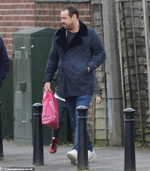 Local time: The former EastEnders actor rocked a navy double-breasted coat with a pair of blue jeans and crisp white sneakers.