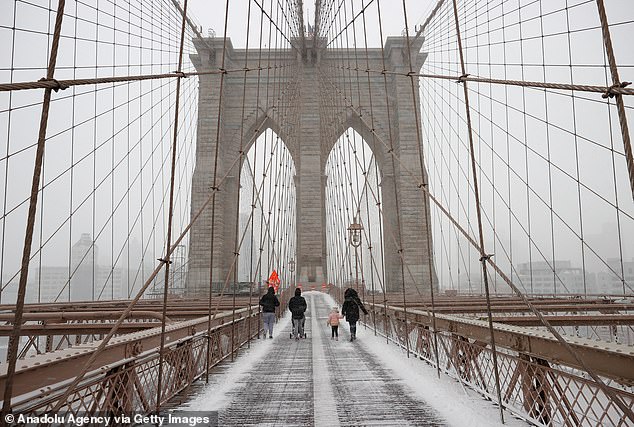 A couple walks across the Brooklyn Bridge as snow blankets New York City, United States, as a massive blizzard hits the East Coast on January 29, 2022.