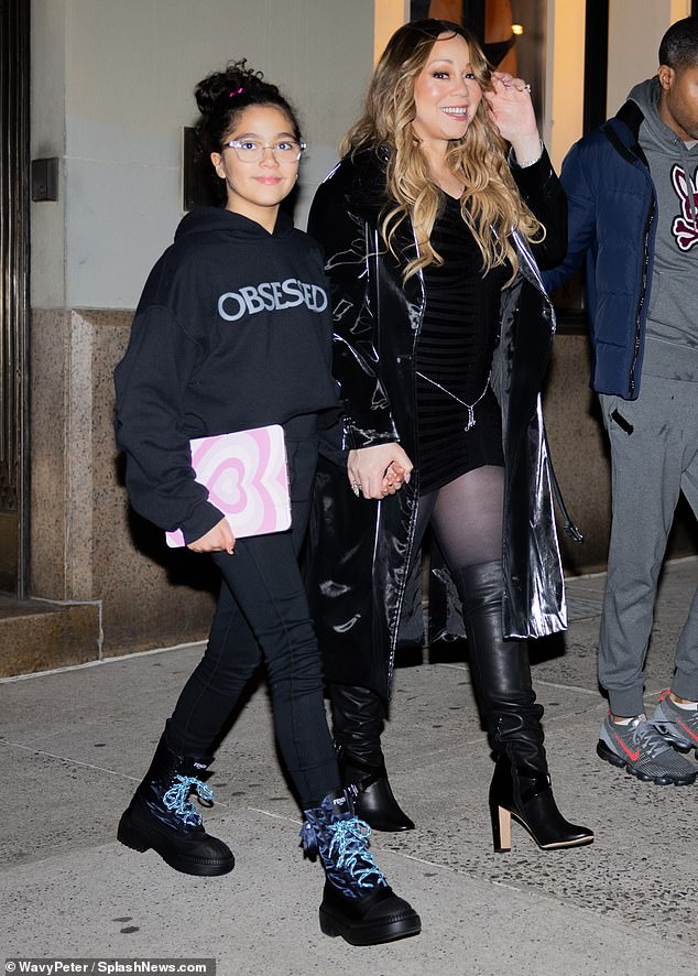 Manhattan chic: The five-time Grammy winner stepped out of her building in knee-high heeled boots and sheer stockings.  A striped black miniskirt covered her body and she donned a spectacular black coat.  Monroe stepped out in blue lace-up boots and a hoodie that honored Mariah's hit song, Obsessed.