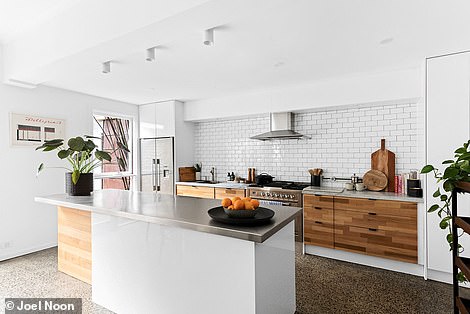 Through the lounge space is a sleek white kitchen with subway tiles, terrazzo floors and stone worktops.