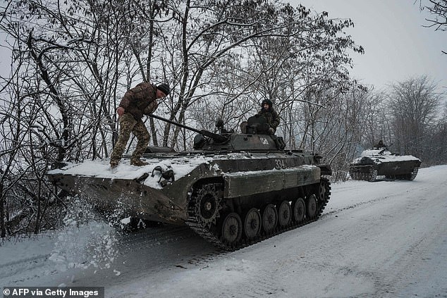 A Ukrainian serviceman uses his foot to remove snow from the top of a BMP-2 infantry fighting vehicle in the Donetsk region on Monday.