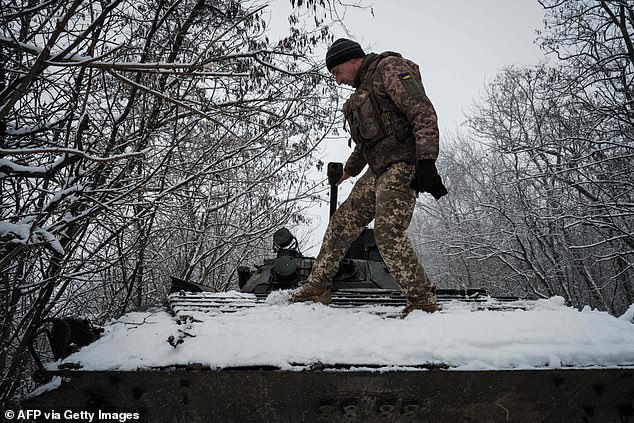 A Ukrainian serviceman uses his foot to remove snow from the top of a BMP-2 infantry fighting vehicle in the Donetsk region on January 30, 2023, amid Russia's invasion of Ukraine.
