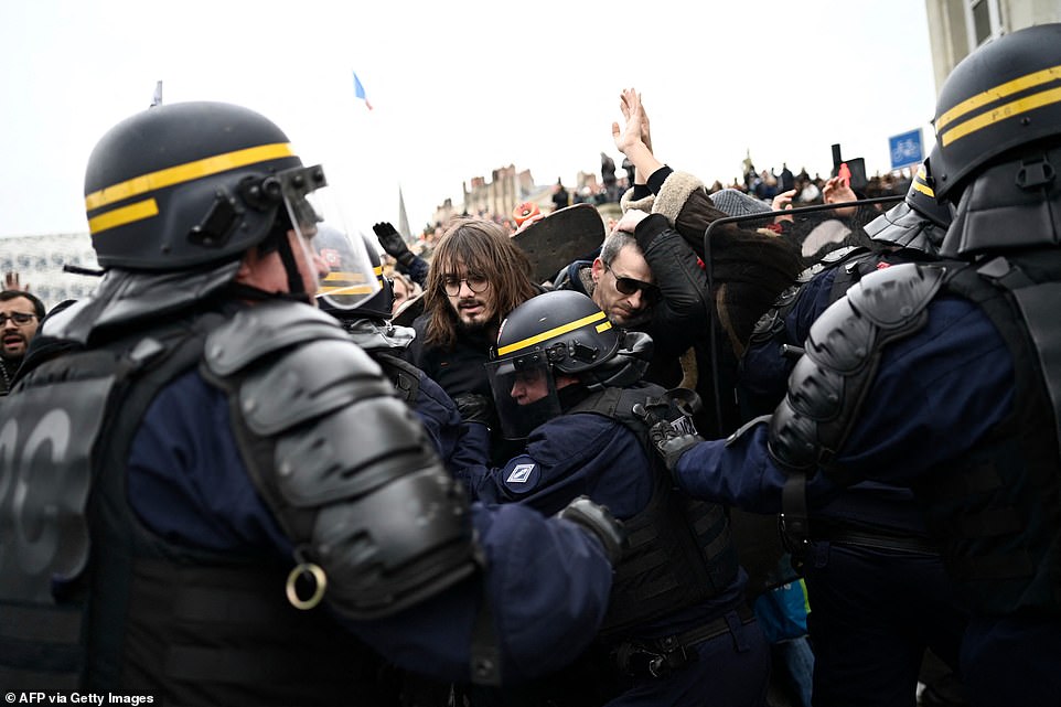 Hundreds of thousands of striking workers descended onto the streets of French cities - from Paris to Marseille - to denounce a reform that raises the retirement age by two years to 64 in a major test to Macron's presidency. Pictured: Protesters clash with riot police during demonstrations in Nantes on Tuesday