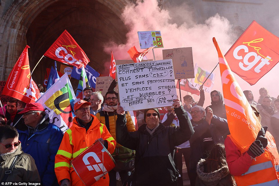 Trade union members hold placards and burn flares during a demonstration on a second day of nationwide strikes and protests over the government's proposed pension reform, in Mende, southern France, on Tuesday
