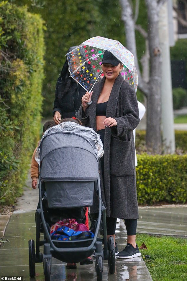 Stay dry: Teigen smiled as she held Luna's umbrella