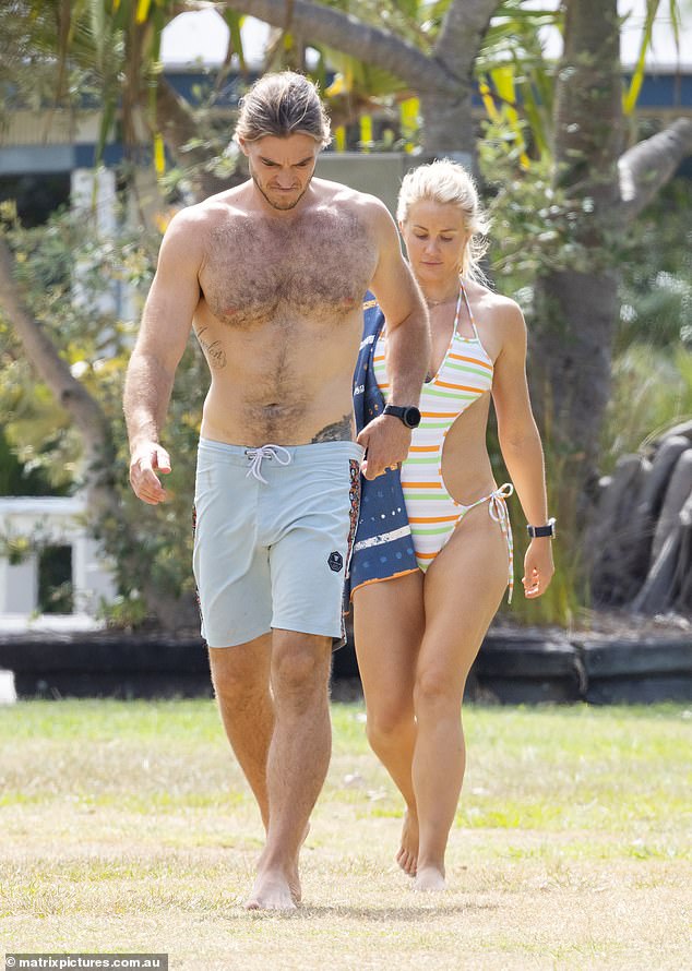 Ali Oetjen (right) stepped out in a revealing swimsuit on Monday while taking a dip in the ocean in Noosa with her new boyfriend Mitch Adams (left)