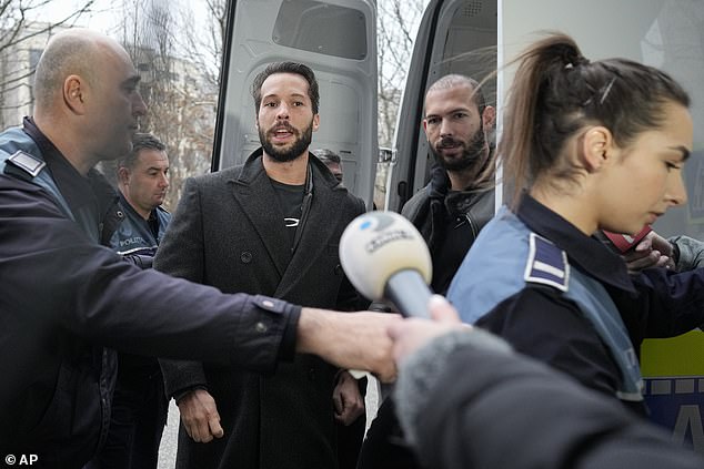 Police officers escort Andrew, right, handcuffed to his brother Tristan, left, outside the Directorate for Investigating Organized Crime and Terrorism (DIICOT) in Romania on Thursday