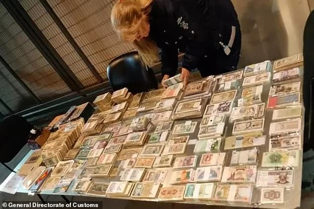 A customs agent in Argentina separates a collection of notes and coins that he seized from a couple on Wednesday after they arrived on a ferry and claimed they had no assets to declare before an officer and sniffer dog made the discovery.