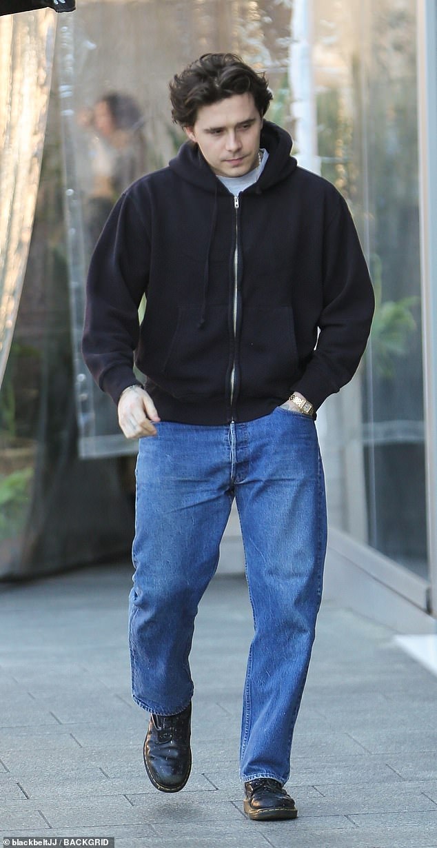 Casual: Brooklyn Beckham headed out to lunch with his wife Nicola in Beverly Hills on Tuesday, looking casual in a black hoodie and jeans