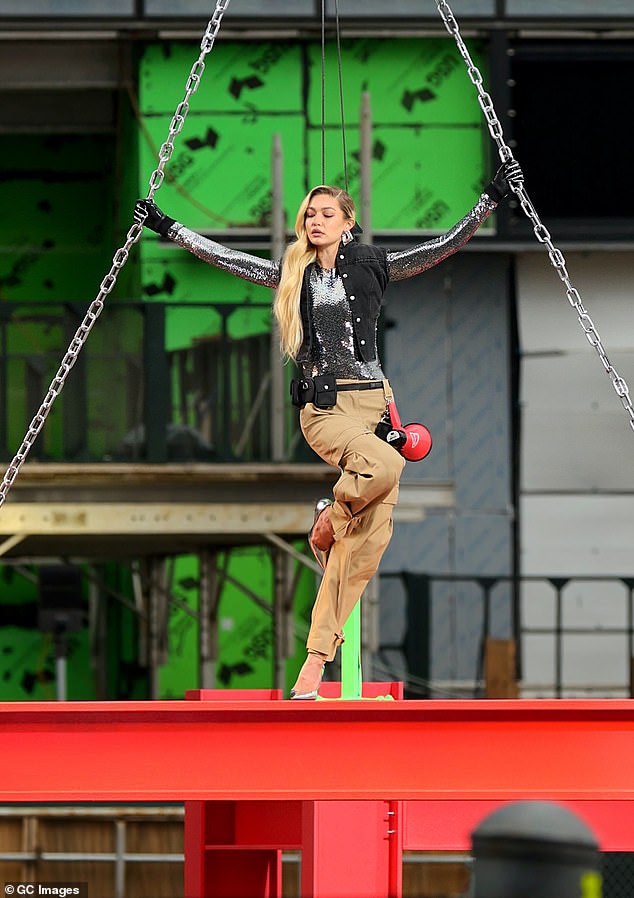 High flying: Gigi Hadid hanging from a steel beam at a construction site in Manhattan's Hudson Yards on Tuesday while filming a commercial for Maybelline