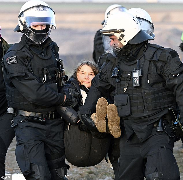 Greta Thunberg was seen smiling as she was taken away by riot police for the second time in three days while protesting at a coal mine in Germany today.