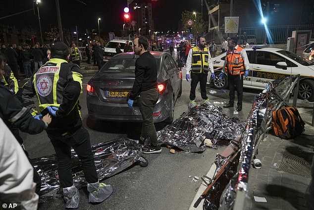 Victims of a shooting attack lie covered on the ground near a synagogue in Jerusalem, Friday, January 27, 2023.