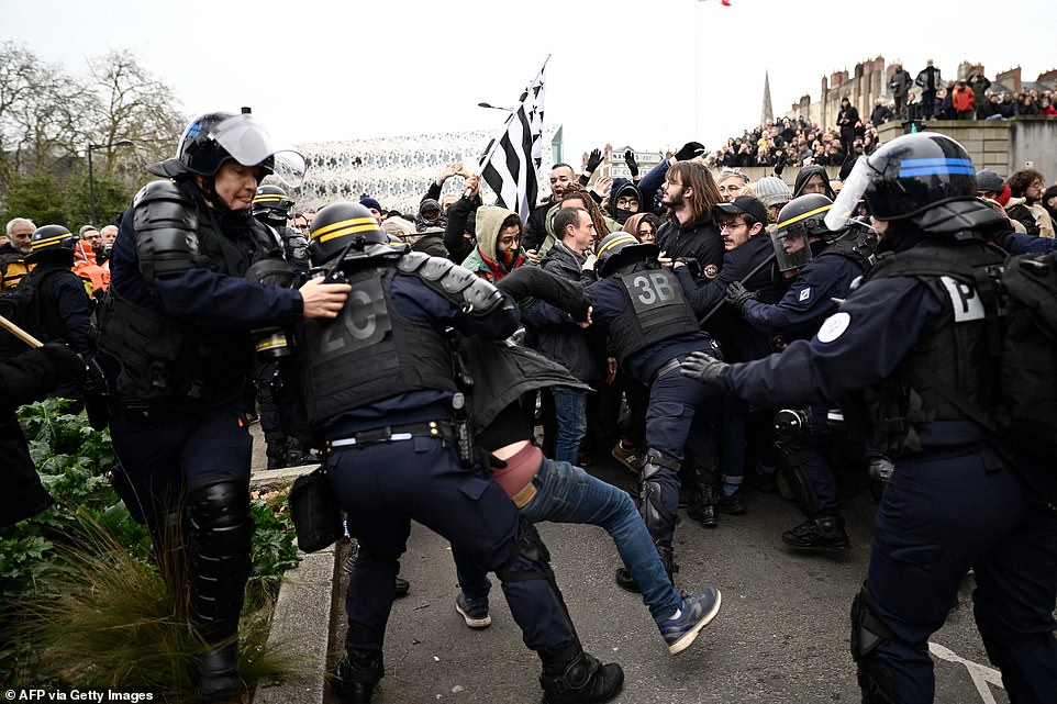 Huge crowds of protesters clashed with riot police in cities across France today in a second day of nationwide protesters over French President Emmanuel Macron's plan to make people work longer before retirement. Pictured: French riot police push back protesters as clashes erupt during a rally on a second day of nationwide strikes and protests over the government's proposed pension reform, in Nantes on Tuesday