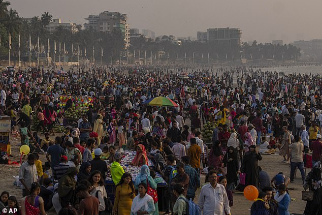 India's population is set to overtake China on April 14 this year to become the world's biggest, a UN report has predicted. Pictured: people crowd a Mumbai beach