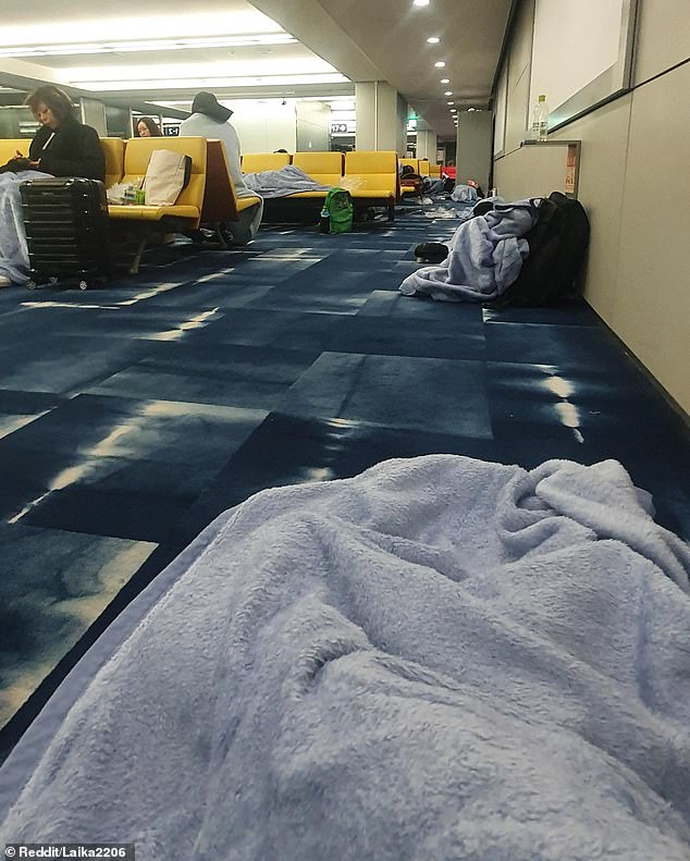 Passengers stranded at Osaka's Kansai International Airport are shown with the blankets they were given at 4 a.m. while waiting for a Jetstar flight delayed by more than 21 hours.