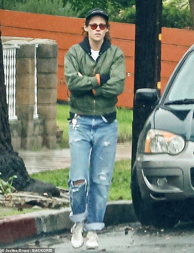 Rainy day: Kristen Stewart braved the rainy weather to go for a walk with a friend in Los Angeles on Sunday.  The 32-year-old actress looked casual in a pair of distressed jeans, sneakers, and she tried to keep warm in a green jacket with a black hood.