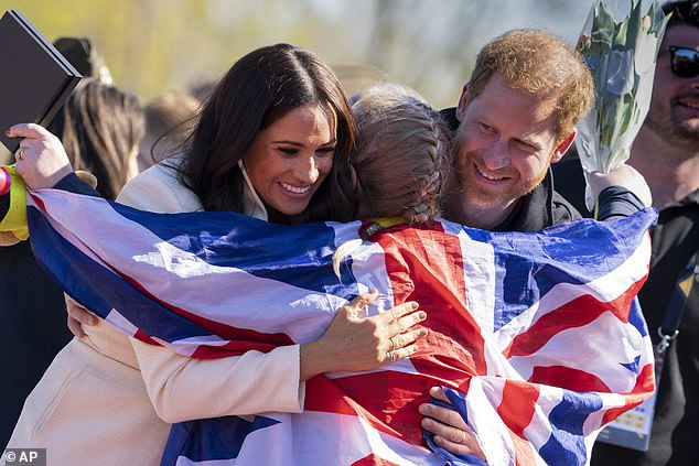 Prince Harry and Meghan Markle, Duke and Duchess of Sussex, hug Lisa Johnston, a former military amputee medic, as she celebrates with her medal at the Invictus Games venue in The Hague, Netherlands, Sunday, April 17, 2022.