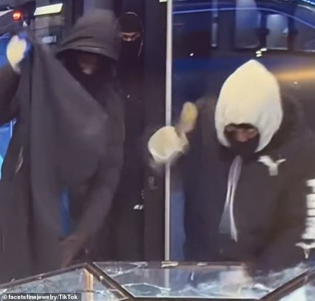 The trio of masked men are seen breaking the main glass screens with hammers.