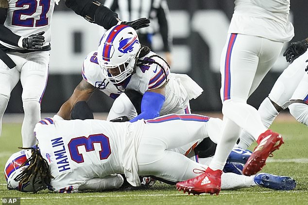 Buffalo Bills safety Damar Hamlin (3) lies on the grass after making a tackle on Cincinnati Bengals wide receiver Tee Higgins, blocked from view, while Buffalo Bills linebacker Tremaine Edmunds (49 ), assists at the end of the play during the first half of an NFL football game between the Cincinnati Bengals and the Buffalo Bills