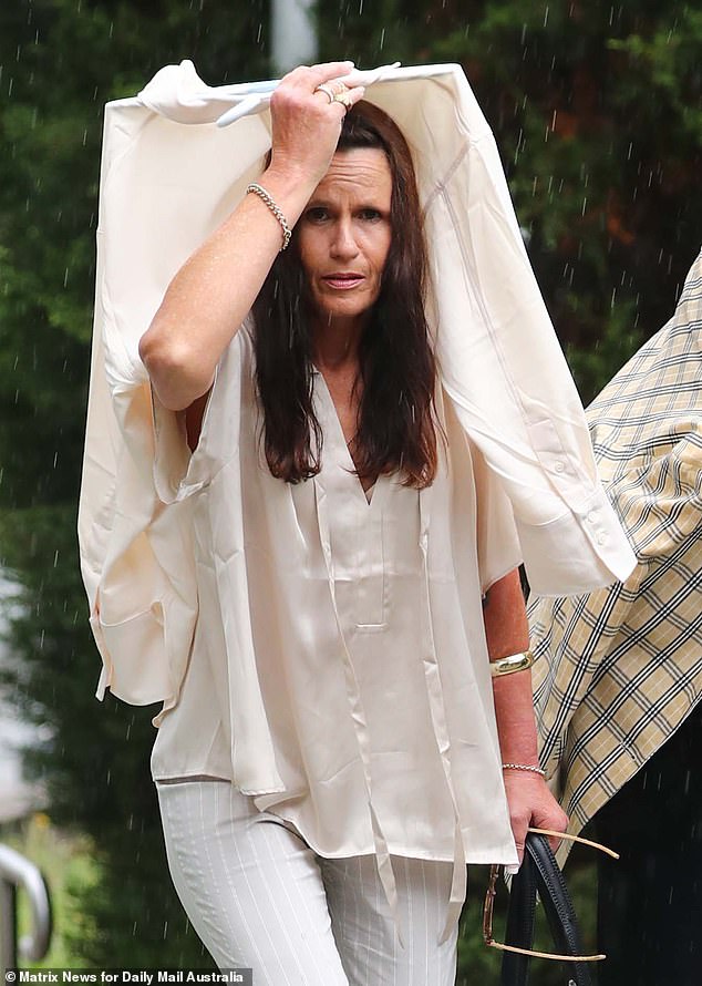 The NRL star's mother, Nicho Hynes, is accused of taking part in a narcotics supply operation in which a man packing heroin died after inhaling the drug.  Julie Hynes is pictured sheltering from the rain outside the District Court in Gosford on Monday.